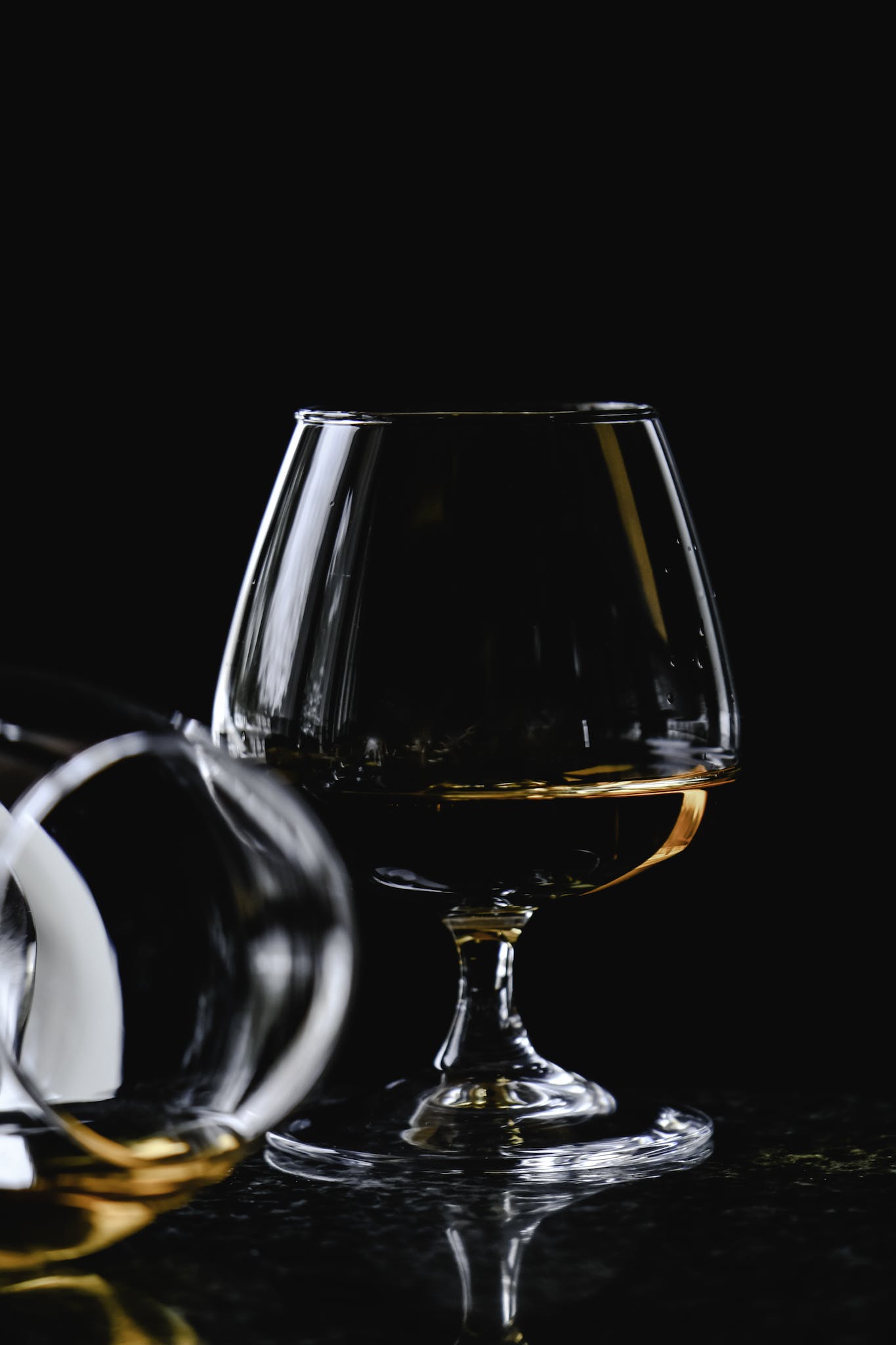 A Wine Glass  with a Brown Liquid on a Dark Background