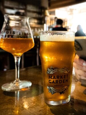 Person Using Smartphone Sitting on a Table with Glasses of Cold Beer